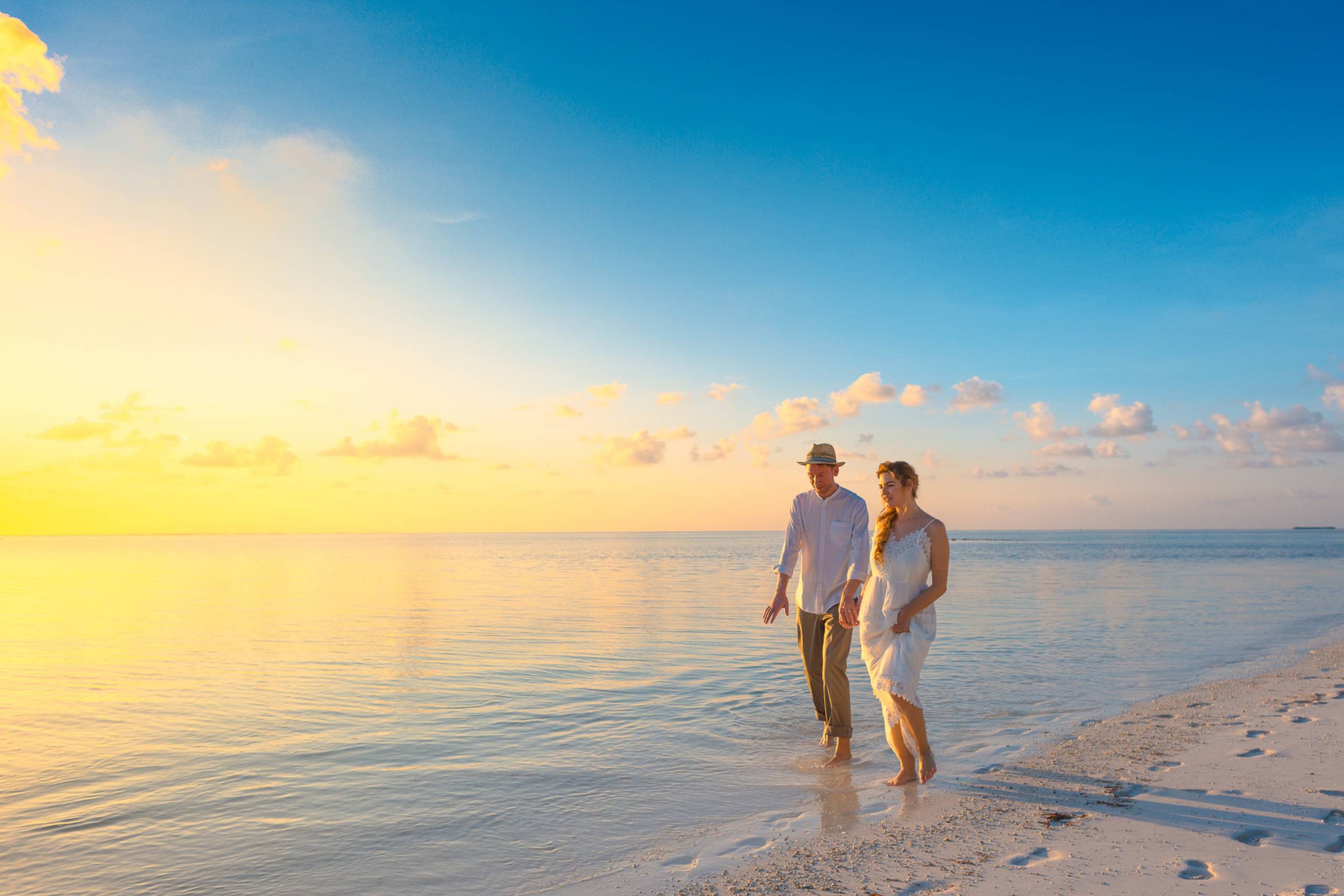 couple-walking-on-seashore-wearing-white-tops-during-sunset-1024989